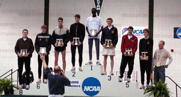 Nate Brigham poses on the podium after his 8th place finish in the 5000.